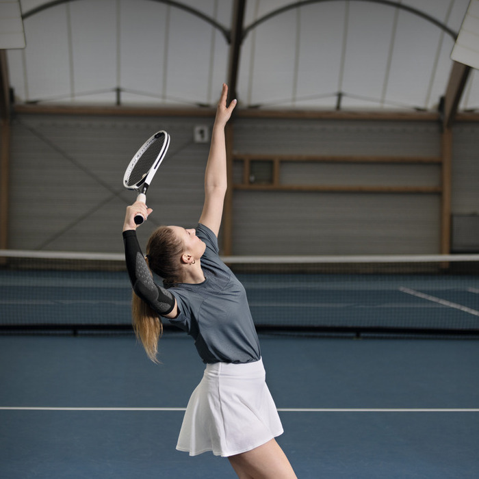 Tennisspielerin beim Aufschlag mit Kompressionsbandage am Arm