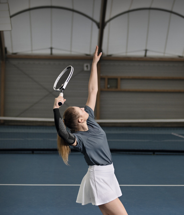 Tennisspielerin beim Aufschlag mit Kompressionsbandage am Arm