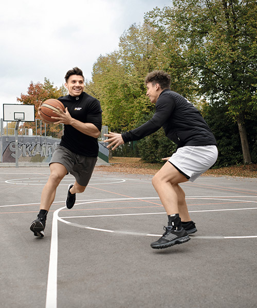 Zwei Sportler spielen gemeinsam Basketball und tragen sportomedix Produkte