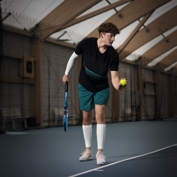 Tennisspieler beim Aufschlag mit Kompressionsbandagen an Arm und Wade